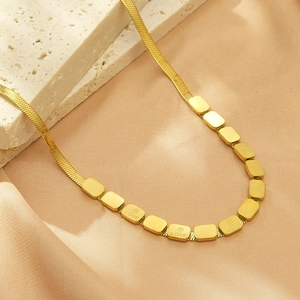 Detail showing golden snake chain necklace with rectangular beads and LOVE engraving