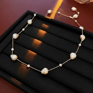 Baroque pearl necklace with gold plated chain on a black jewelry display tray