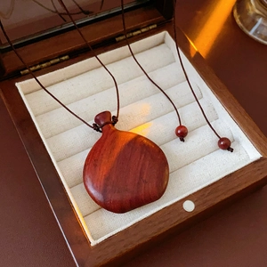 Macro detail of a vintage teardrop wooden pendant on beige velvet inside a jewelry box