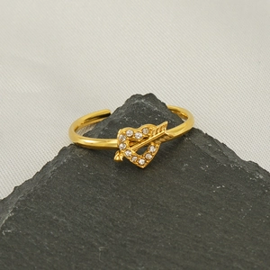 Macro shot of 18k gold plated arrow through heart ring with zircons on dark stone