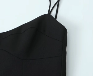 Gros plan de la robe noire à bretelles montrant l'encolure festonnée et les fines brides