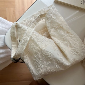 Close-up of white lace embroidery floral pattern and simple tag on cotton tote bag