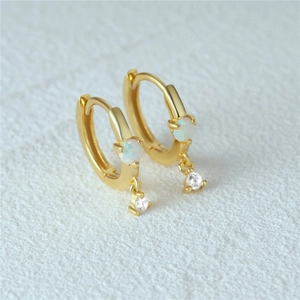 Macro shot of gold hoop earrings featuring white opal stones and sparkling zircon charms