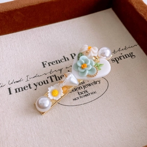 Macro view of mint green floral hair clip with white pearls and delicate resin petals