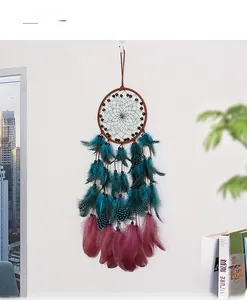 Bohemian dream catcher with brown frame and feathers hanging on white wall