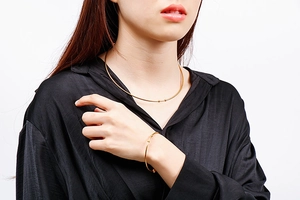Detail view of gold stainless steel choker and matching cuff bracelet set on model
