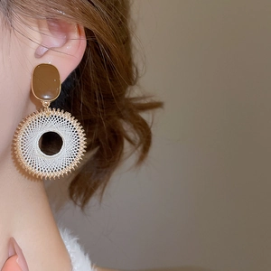 Close-up of bohemian resin woven hoop earrings worn on ear in warm summer style