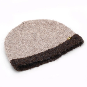 Detail of knit bucket hat featuring a golden rose emblem and two-tone texture