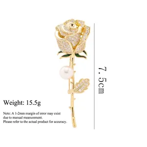Elegant gold rose brooch with white zircons, green enamel leaves, and a pearl accent