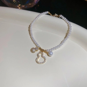 Détail d'un bracelet en perles avec breloques gourdes dorées et strass étincelants