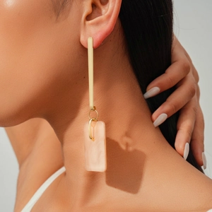 Detail of geometric drop earrings featuring gold metal bar and marble resin rectangle