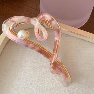 Detail of pink acetate heart hair claw clip with pearl accent on a golden metal base