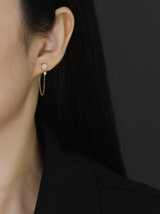Close-up of a gold plum blossom earring with a delicate CZ tassel chain on a model