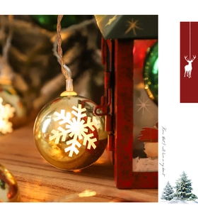 Macro detail of warm LED Christmas bulb with white snowflake pattern and festive pine background