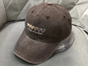 Close-up of brown washed cotton baseball cap with heart embroidery and one day at a time text