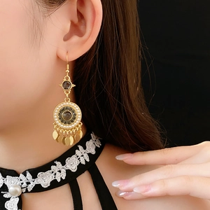 Gros plan sur les boucles d'oreilles dorées à glands avec perles rondes et cristaux