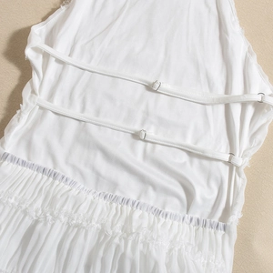 Detail view of white backless dress with adjustable straps and lace ruffled hem texture