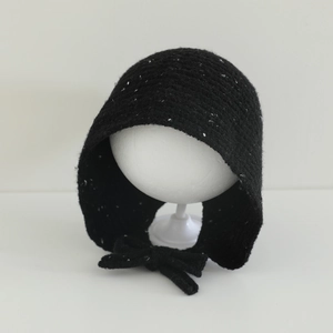 Détail du bonnet en tricot noir moucheté de blanc avec attaches pour l'hiver
