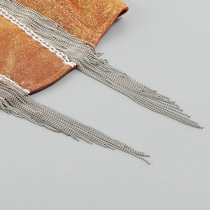 Detailed macro view of orange shimmer fabric with hanging silver metallic ball fringe