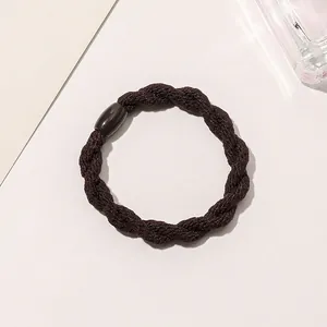 Macro detail of dark brown braided hair tie with a smooth oval decorative buckle