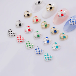 Macro detail of heart-shaped checkerboard nail charms with rhinestones and colorful oil drip