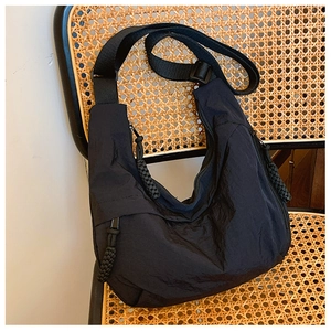 Dettaglio borsa a mezzaluna in nylon nero con cerniera intrecciata su sedia di vimini