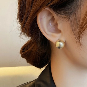 Minimalist 18K gold hollow geometric sphere stud earrings worn by a model in warm light