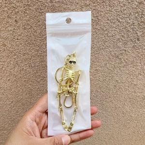 Detailed view of a gold skull keychain charm in clear packaging with a white header card