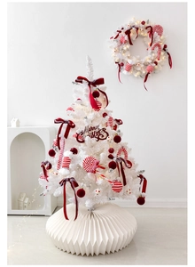 Close-up of white Christmas tree and matching wreath with festive red bow decorations