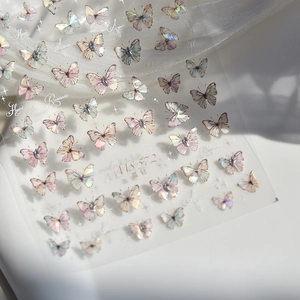 Detailed macro of 3D metallic butterfly nail stickers with crystals on white silk