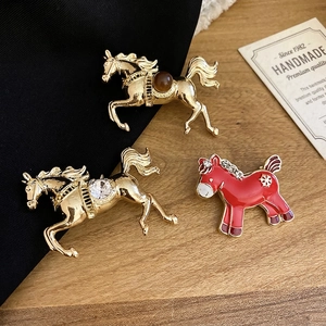 Elegant gold-tone horse brooches featuring crystal inlay and resin horse designs on dark fabric