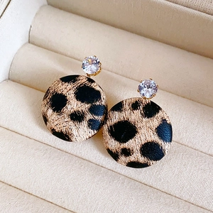 Detailed shot of leopard print hoop earrings with a sparkling zircon stud in a beige jewelry box