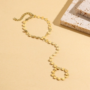 Detail of gold finger chain bracelet with small metal discs and adjustable lobster clasp