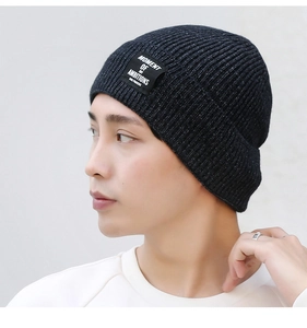 Detail of navy blue knit beanie with sequin accents and a woven message patch