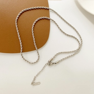 Detailed view of a silver twist chain necklace with lobster clasp on leather mat