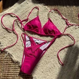 Detail showing hot pink bikini top with white pearl beads and high-cut cross waistband