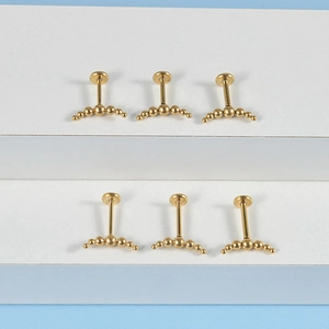Detail showing six curved golden stainless steel labret studs on a white background