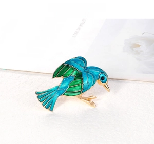 Macro shot of bird brooch with blue enamel and gold plating on a textured surface