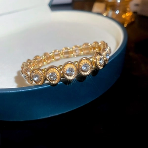 Detailed macro shot of oval links with sparkling zircons on a gold-plated stretch bracelet