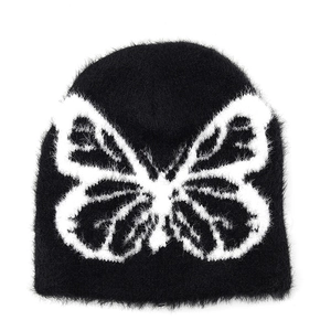 Detailed view of black plush beanie featuring a large white knitted butterfly pattern