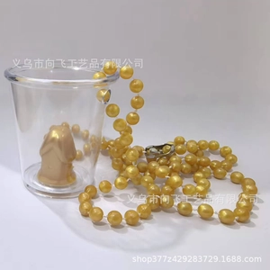 Close-up of golden beaded chain necklace with metallic luster on transparent cup