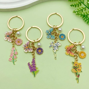 Detailed view of enamel butterfly and flower keychain charms with pearls and gold rings