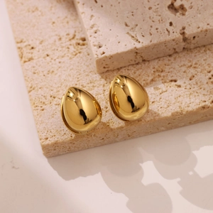 Polished gold drop earrings in minimalist teardrop shape displayed on natural stone