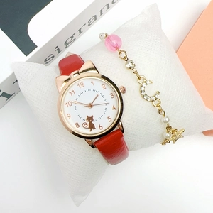 Red leather strap watch with cat dial and star moon bracelet on a white pillow