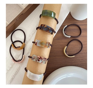 Detail of assorted acetate ponytail holders with handmade lettering on a wooden tray