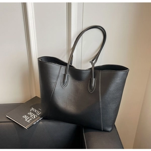 Detailed close-up of a minimalist black leather tote bag on a stylish sofa