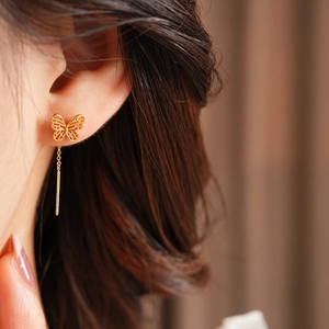 Close-up of a gold butterfly threader earring featuring a hollow design and long metal chain