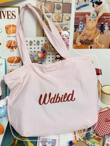 Detail of pink canvas tote bag with red script logo and spacious drawstring opening