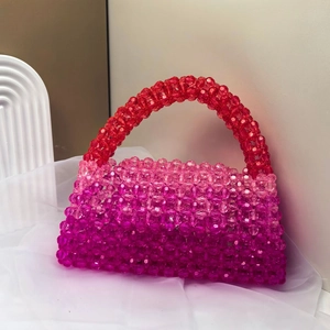 Close-up of handmade beaded bag featuring red gradient acrylic beads on white fabric