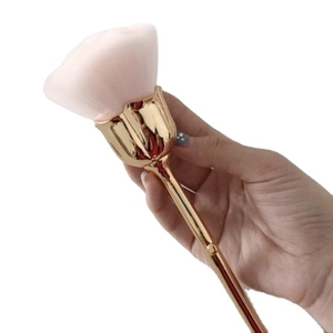 Rose shaped makeup brush with gold handle and pink gradient bristles on white background
